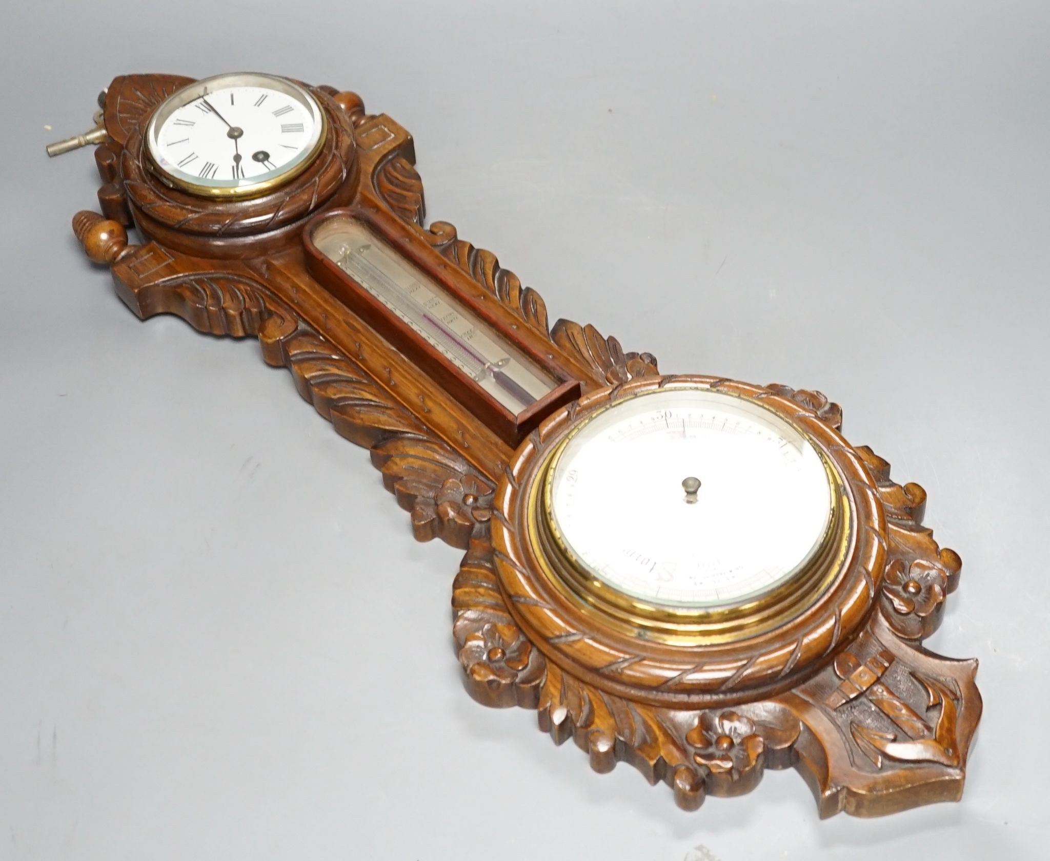 A Victorian carved walnut aneroid barometer with timepiece